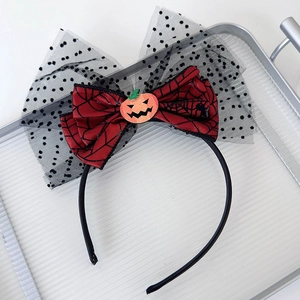 Detail of Halloween headband with black mesh bow, spider web patterns, and small pumpkin