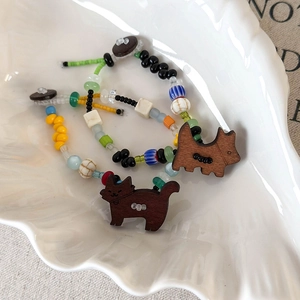 Détail macro de bracelets en perles colorées avec pendentifs chiot et chaton en bois sur plat