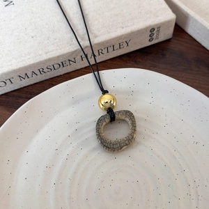 Detail view of retro camel bone style ceramic ring pendant on a long black necklace cord