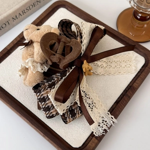 Detail of plush bear hair claw with brown silk bow and coffee plaid ribbon detail