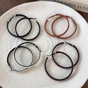 Detailed close-up of four assorted colorful leather wrap hoop earrings on a ceramic tray