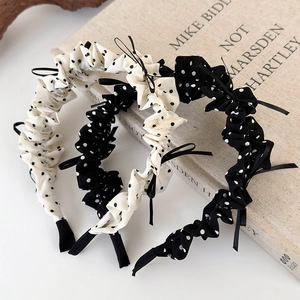 Polka dot ruffled headband with delicate bow detail on vintage book background