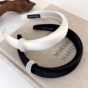 Close-up of handmade wide satin headband with triple-row pearl embellishment