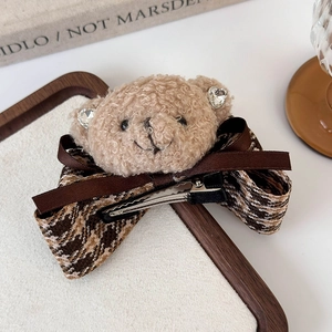 Close-up of cute plush teddy bear hair clip with brown ribbon and houndstooth pattern bow