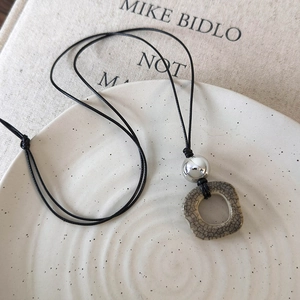 Macro detail of camel bone pendant necklace on ceramic tray with art book background