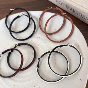 Top view of large leather-wrapped hoop earrings in four colors on a white ceramic tray