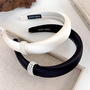 Detail view of premium black and cream satin padded headbands with triple pearl center buckle