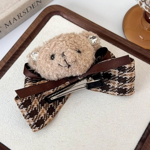 Detail of plush bear hair clip with houndstooth bow and satin ribbon on metal duckbill clip