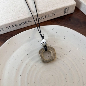 Detail of vintage square ceramic pendant with ice crackle glaze and silver bead on black cord
