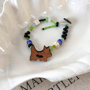 Gros plan d'un bracelet de perles fait main avec breloque chien en bois coloré