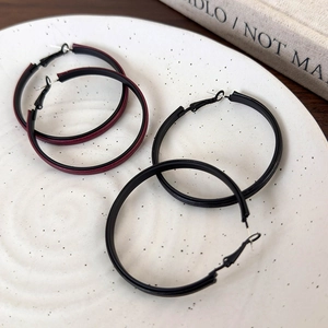 Detail of burgundy and black leather hoop earrings on a decorative ceramic tray
