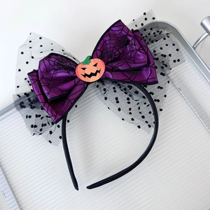 Close-up of Halloween bow headband with spider web pattern and orange pumpkin detail