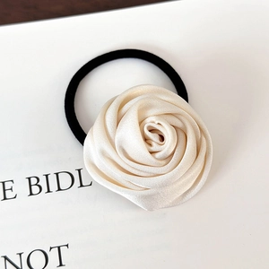 Detail eines eleganten Satin-Kamelien-Haargummis in Creme mit schwarzem Gummiband