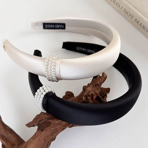 Detail of elegant satin headbands with three rows of white pearls on vintage wood