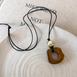 Macro detail of camel bone pendant with golden bead on a minimalist necklace