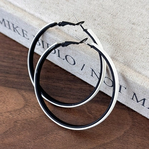 Detail of large black and white contrast hoop earrings on a vintage wooden surface