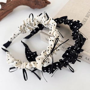 Close-up of pleated polka dot headbands with ribbon bows in black and white styles