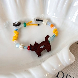Détail du bracelet fait main en perles colorées avec pendentif chat en bois sur plateau