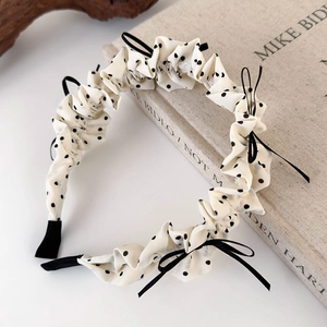 Detail of polka dot pleated headband with black bows on a textured book prop
