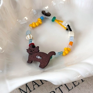 Détail d'un bracelet de perles colorées en résine avec un charm chiot en bois sur plateau