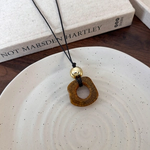 Close-up of irregular brown camel bone pendant with gold bead and vintage texture details