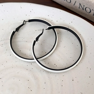 Close-up of black and white contrast hoop earrings on a decorative ceramic tray