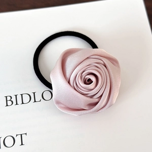 Detaillierte Nahaufnahme eines rosa Satin-Rosen-Haargummis mit Satin-Glanz-Stofflagen