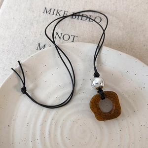 Close-up of vintage camel bone pendant with brown cracked texture and silver bead detail