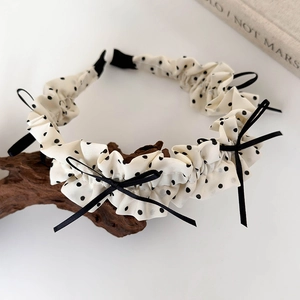 Detailed view of pleated polka dot headband with delicate black ribbon bows on wood