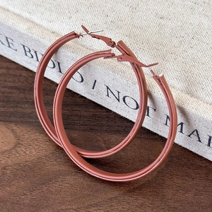 Close-up of large matte brown leather hoop earrings resting on a light fabric surface