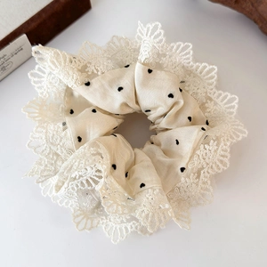 Dettaglio dell'elastico scrunchie crema a pois con bordo in pizzo per capelli