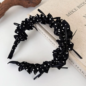 Close-up of black and white polka dot headband featuring ruffled edges and a bow