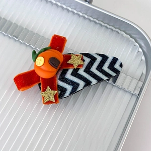 Detailed close-up of velvet bow hair clip with pumpkin and star charms for Halloween