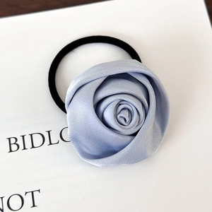 Nahaufnahme von handgefertigtem hellblauem Satin-Rosen-Haargummi mit schwarzem Gummiband