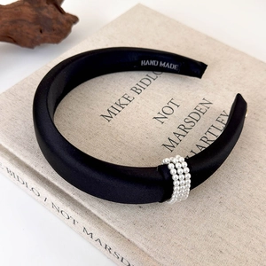 Detail of handmade black satin headband with three rows of elegant white pearls