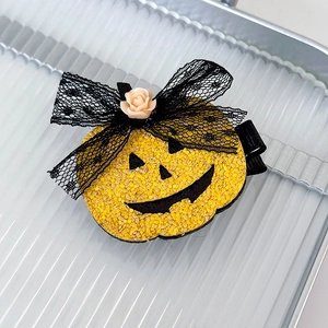 Close-up of Halloween pumpkin hair clip with sequins, lace bow and resin rose detail