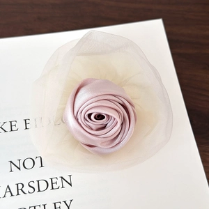 Detail von zartrosa Satin-Rosen-Haarspange mit weißen Netzblüten auf Buchhintergrund