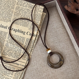 Détail macro du pendentif rond en résine effet marbre sur un collier en cordon brun