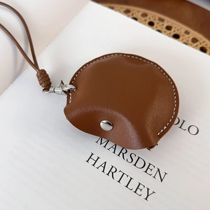 Gros plan d'une pochette en cuir marron avec coutures contrastées et bouton-pression en métal
