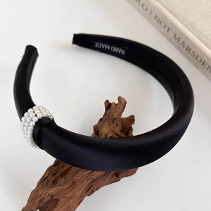 Luxurious black padded headband with three rows of elegant white pearls on satin fabric