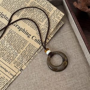 Vue détaillée du pendentif circulaire rétro marbré avec cordon tressé foncé