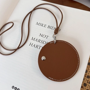 Détail macro du porte-monnaie en cuir marron avec coutures blanches et rivet