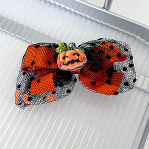 Detail of Halloween bow hair clip featuring orange polka dots and mesh with pumpkin charm