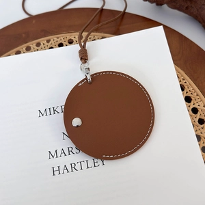 Détail d'un porte-monnaie rond en cuir marron avec surpiqûres blanches et bouton pression