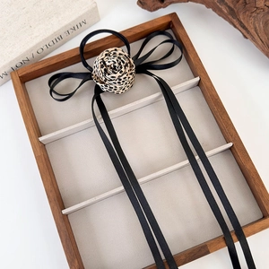 Elastico per capelli con rosa leopardata e lunghi nastri neri su vassoio in legno