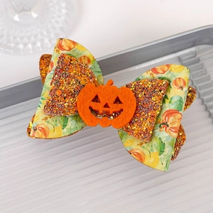 Detail showing a Halloween hair bow with orange pumpkin print and gold sequins finish