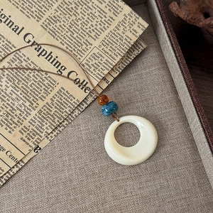 Gros plan du pendentif anneau rétro avec perles d'ambre sur un plateau texturé