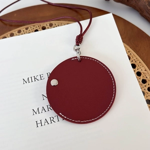 Détail du mini sac de cou en cuir bordeaux avec coutures contrastées et attaches argentées