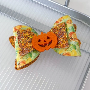 Detail of Halloween bow hair clip featuring an orange felt pumpkin and glitter sequins