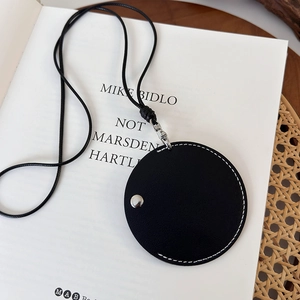 Détail d'une mini pochette en cuir noir avec surpiqûres blanches et bouton argenté